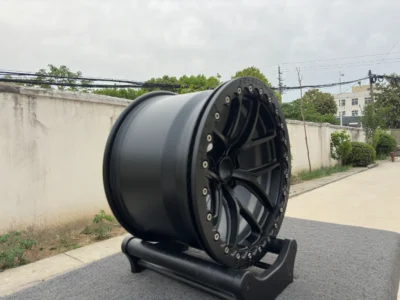 High-quality black alloy wheel displayed outdoors, showcasing detailed design and craftsmanship on a stand.