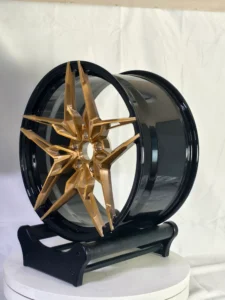 Stylish gold and black alloy wheel displayed on a stand, showcasing a modern, dynamic design perfect for custom vehicles.