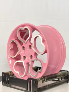Pink alloy wheel with heart-shaped cutouts, showcasing a stylish and unique design for automotive enthusiasts.