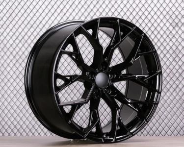 Glossy black alloy wheel with a modern design, set against a textured background for an automotive showcase.