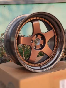 Aluminum alloy wheel featuring a bronze finish and five-spoke design, displayed outdoors on a cardboard box.
