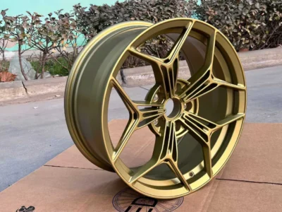 Gold alloy wheel with a modern design, showcased against a blurred background, emphasizing its sleek finish and style.