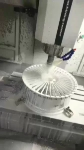 CNC machine cutting a metal wheel, showcasing precision machining and coolant spray in a manufacturing setting.