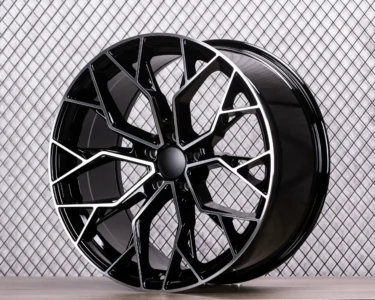 Black alloy wheel with modern design, showcasing intricate spokes against a textured background. Ideal for automotive enthusiasts.
