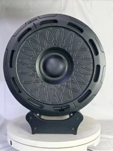 Black decorative disc with a geometric design, displayed on a round white pedestal against a neutral background.