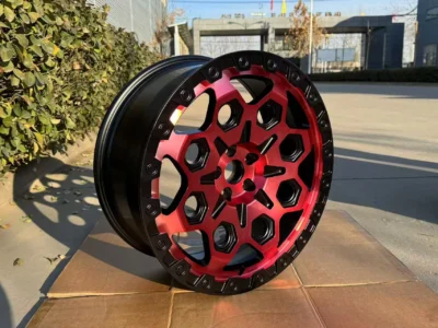 Stylish red and black alloy wheel displayed outdoors, showcasing intricate design and high-performance features.