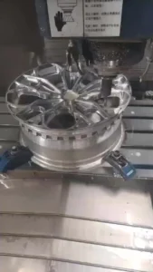 CNC machine crafting a detailed aluminum wheel, showcasing precision manufacturing in automotive production.
